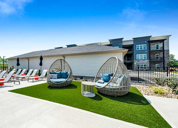 A modern outdoor seating area with white lounge chairs and blue cushions.
