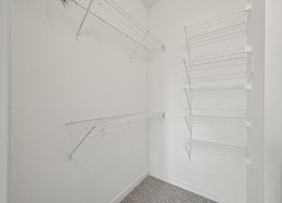 Empty white closet with shelves and hangers.