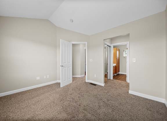 A room with a carpeted floor and two doors.