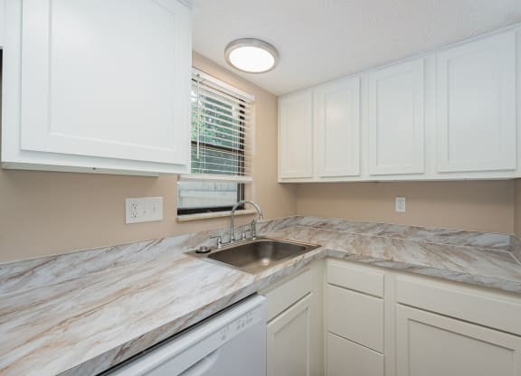a kitchen with white cabinets and marble counter tops and a sink
