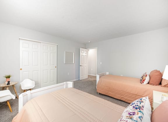 a bedroom with two beds and a chair and a table
