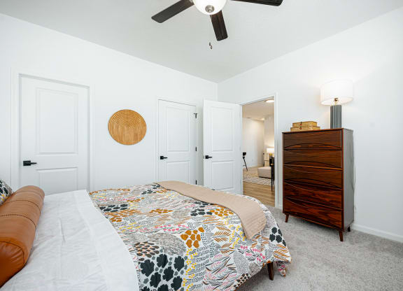 a bedroom with a bed and a dresser and a ceiling fan