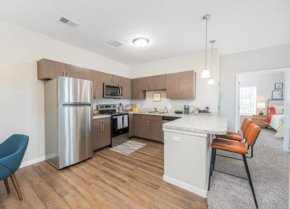 a kitchen and living room with a bar stool and a refrigerator