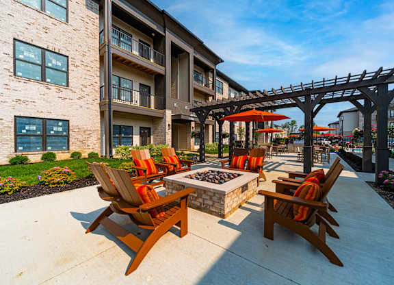 A patio with a fire pit and chairs.