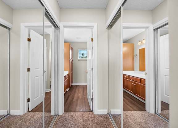 A hallway with white doors and brown carpeting.