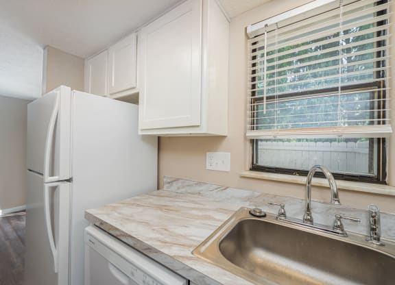 a kitchen with a sink and refrigerator and a window