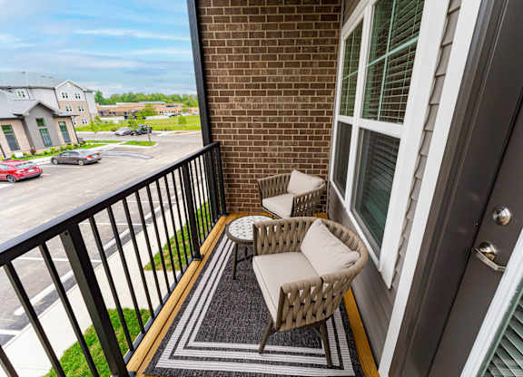 A balcony with a wicker chair and table.