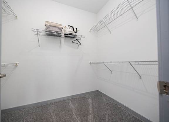 A walk-in closet with a grey carpet and metal racks.