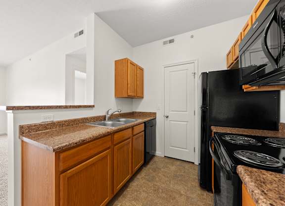 A kitchen with a black oven and brown countertops.