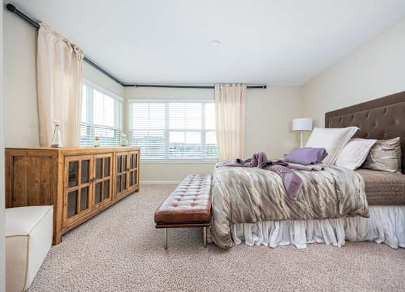 A bedroom with a large bed and a wooden cabinet.
