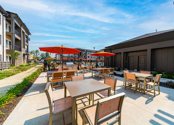 A patio with tables and chairs is surrounded by buildings.