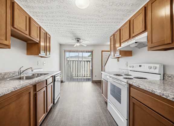 A kitchen with wooden cabinets and a white stove top oven.