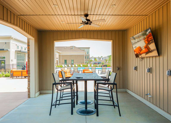 a patio with a table and chairs and a ceiling fan