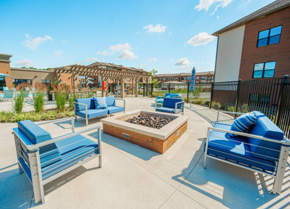 a patio with blue chairs and a fire pit