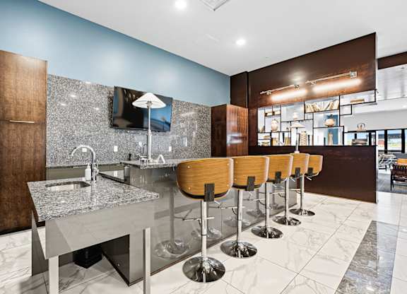 A modern bar with a row of stools and a counter.