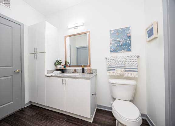 A white bathroom with a toilet, sink, and mirror.