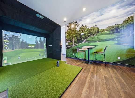 A room with a golf simulator and a wall mural of a golf course.