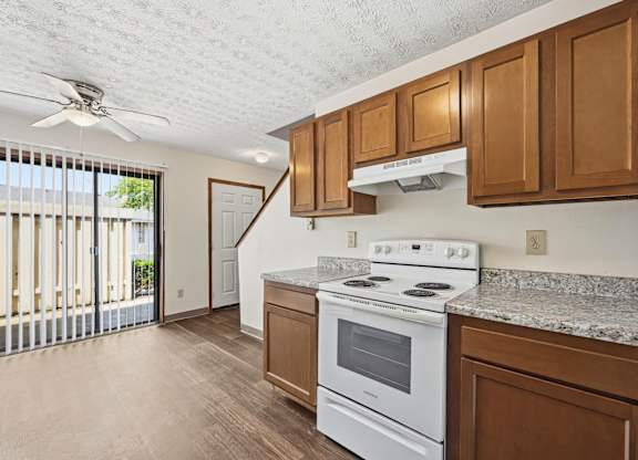 A kitchen with a white stove top oven and wooden cabinets.