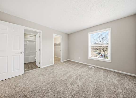 A room with a carpeted floor and a window showing a tree outside.