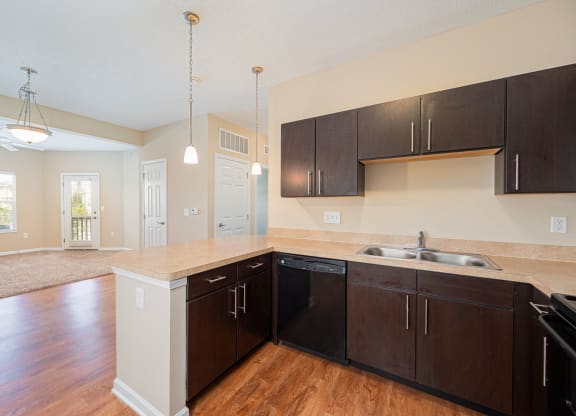 an empty kitchen with wooden floors and black cabinets