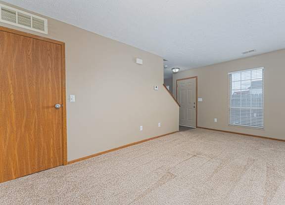 A room with a carpeted floor and a wooden door.