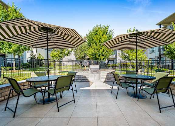 A patio with tables and chairs under striped umbrellas.
