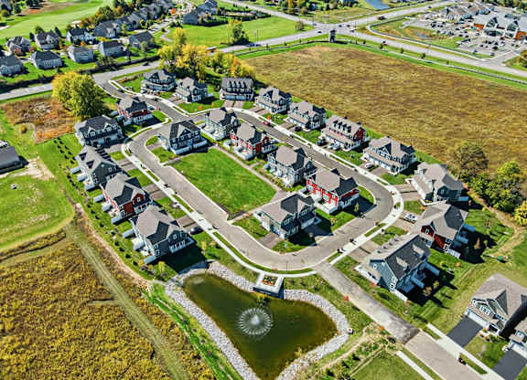 A bird's eye view of a residential neighborhood with houses and a pond.