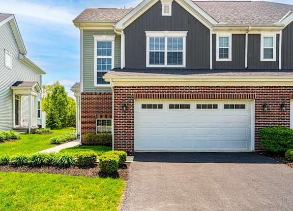 A house with a grey garage door in front of it.