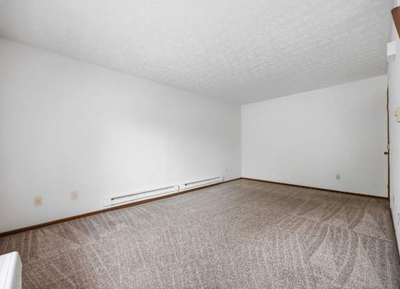 A room with a carpeted floor and a window with blinds.
