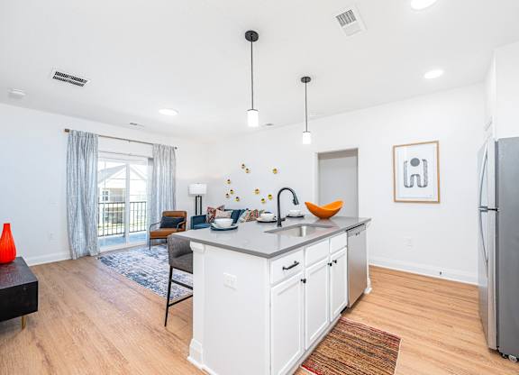 A kitchen with white cabinets and a grey refrigerator.