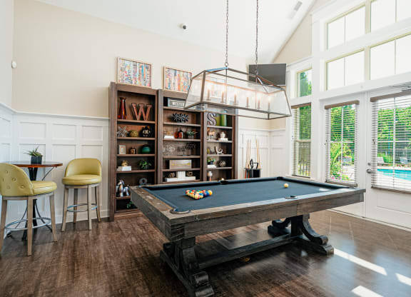 a pool table in a living room with a light hanging over it