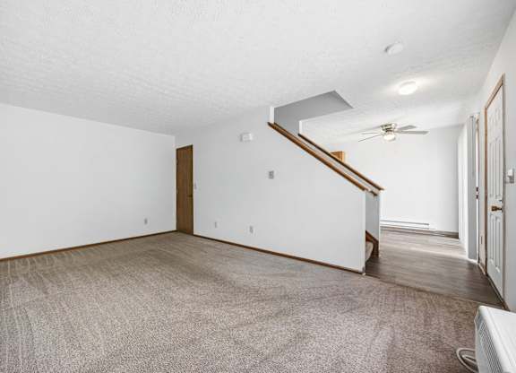 A room with a carpeted floor and a staircase.