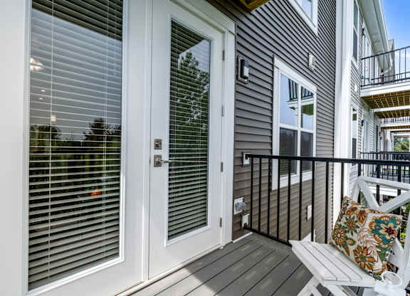 A white door with a window above it and a balcony to the right.