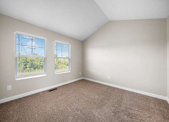 A room with two windows and carpeted floor.