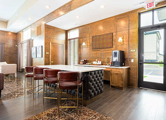 A bar area with a white counter and red chairs.