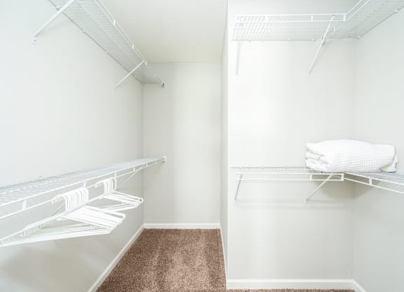 a walk in closet with a mirrored closet door and a shelf with towels