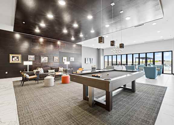 A billiard table is in the middle of a room with a grey carpet.