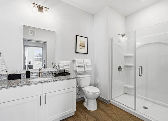 A white bathroom with a toilet, sink, and shower.