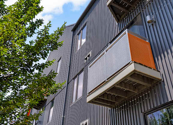 A building with a grey facade and a balcony with an orange railing.