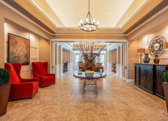 a lobby with red chairs and a table and a chandelier