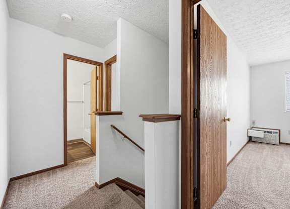 A white room with a brown door and a carpeted floor.