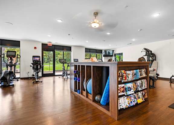A gym with a variety of equipment and a wooden shelf with colorful items.