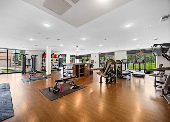 A gym with a variety of equipment including treadmills, weights, and exercise machines.