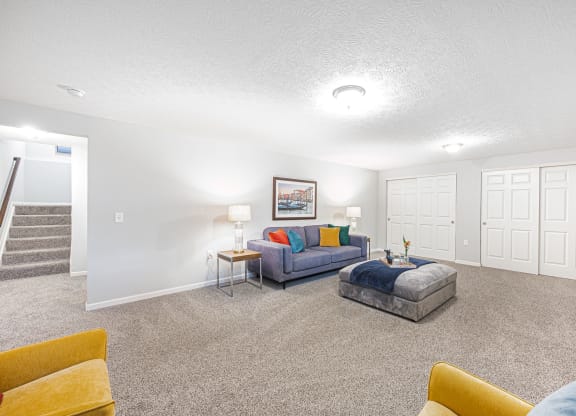 a finished basement with couches and a chair and a table