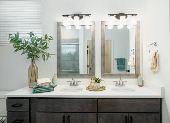 a bathroom with two sinks and three mirrors