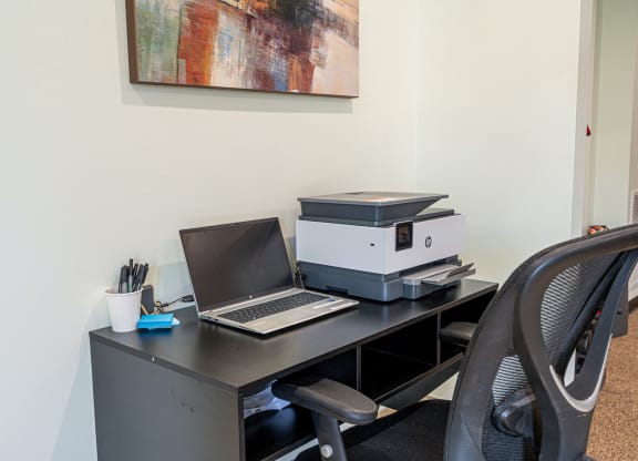 an office desk with a laptop computer and a printer on it