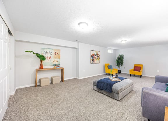 a finished basement with a couch and chairs and a