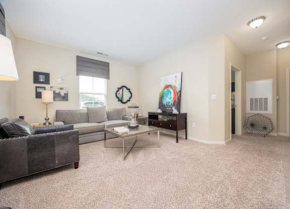 A living room with a grey couch, a coffee table, and a painting on the wall.