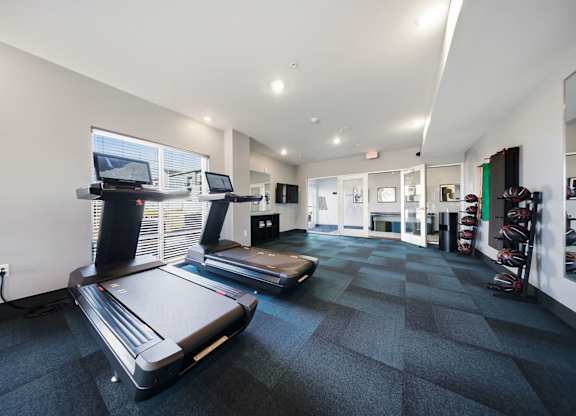 A treadmill and a stationary bike are in a spacious gym.
