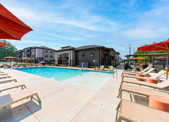 A pool surrounded by sun loungers and umbrellas.